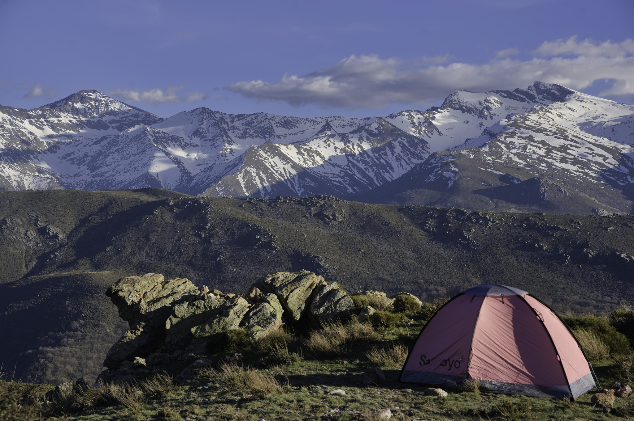 Campsite with a view! Center section of Sierra Nevada ridge from Mulhacen to Veleta
Some illuminated rocks in the foreground with a low lying ridge middle distance and some dramatic snow clad peaks beyond
