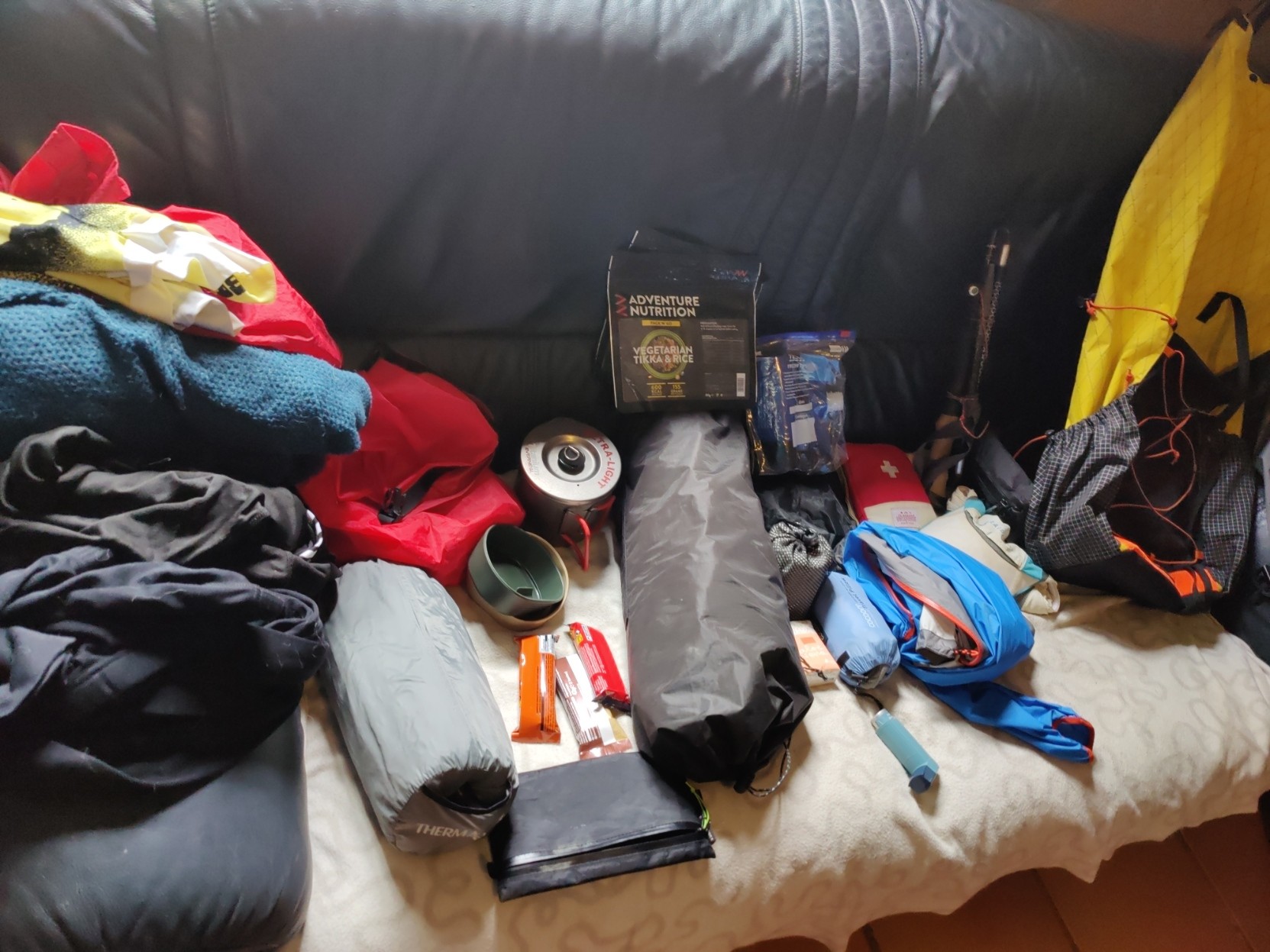 A colourful selection of mountain outdoor gear sits displayed on a black sofa