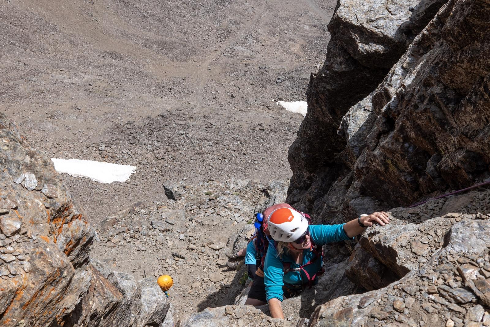 @khusky with a white and orange helmet ascending a short wall to the summit of Veleta in Spain's Sierra Nevada mountains