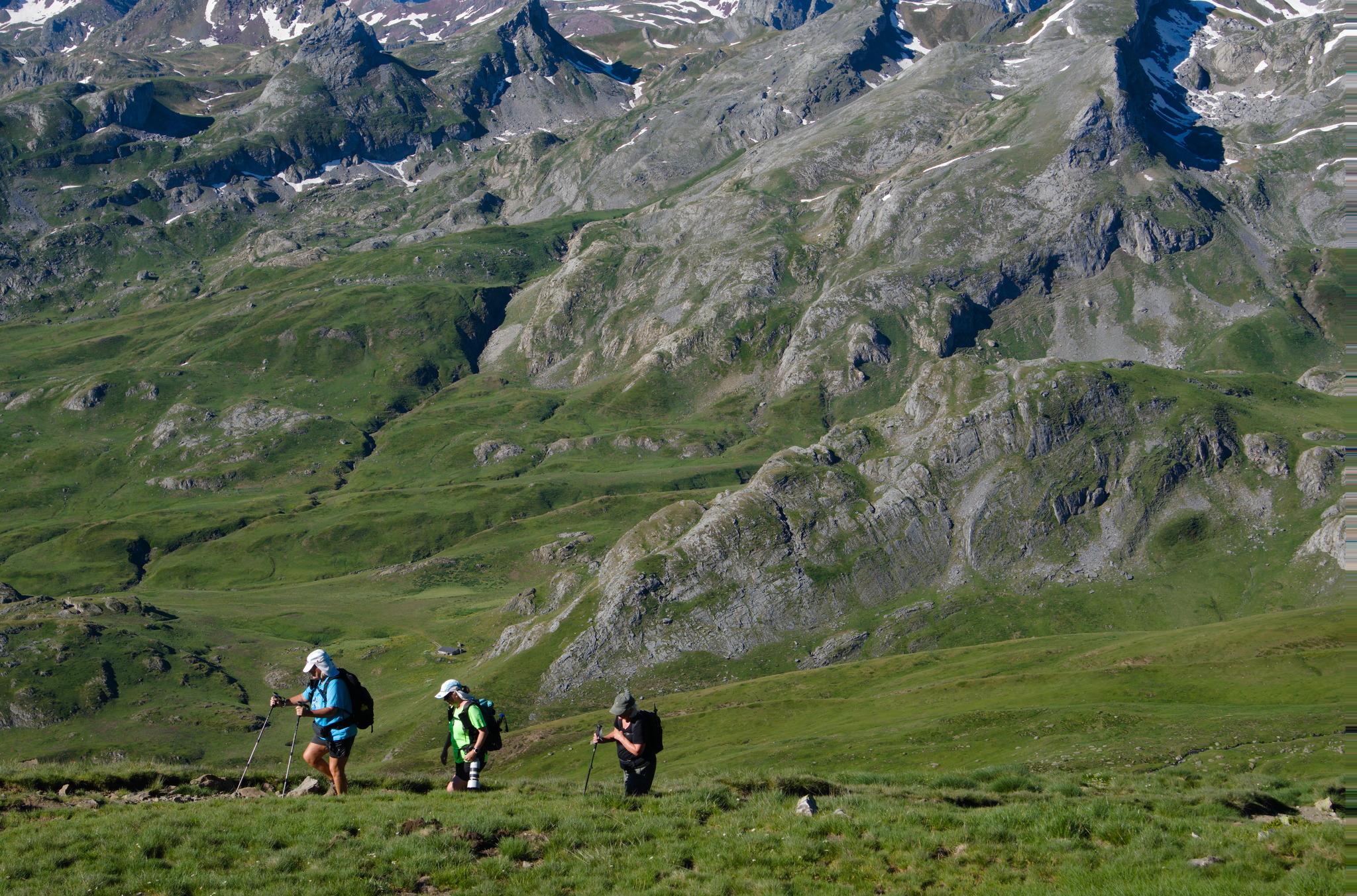 Hikers on a oath with green valleys and grey rock slave in the distance