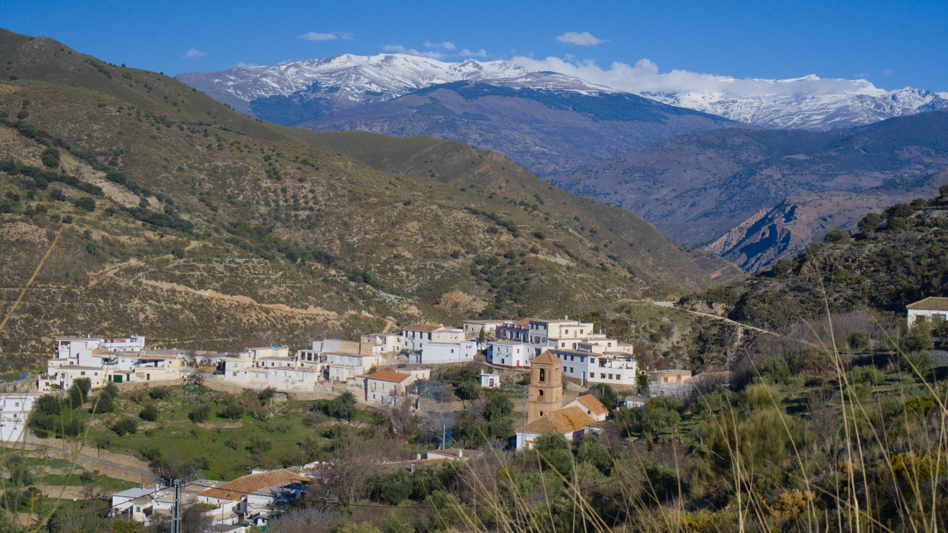 The small, traditional village of Alcazar in the Sierra de Contraviesa backed by the snow clad mountains of the Sierra Nevada