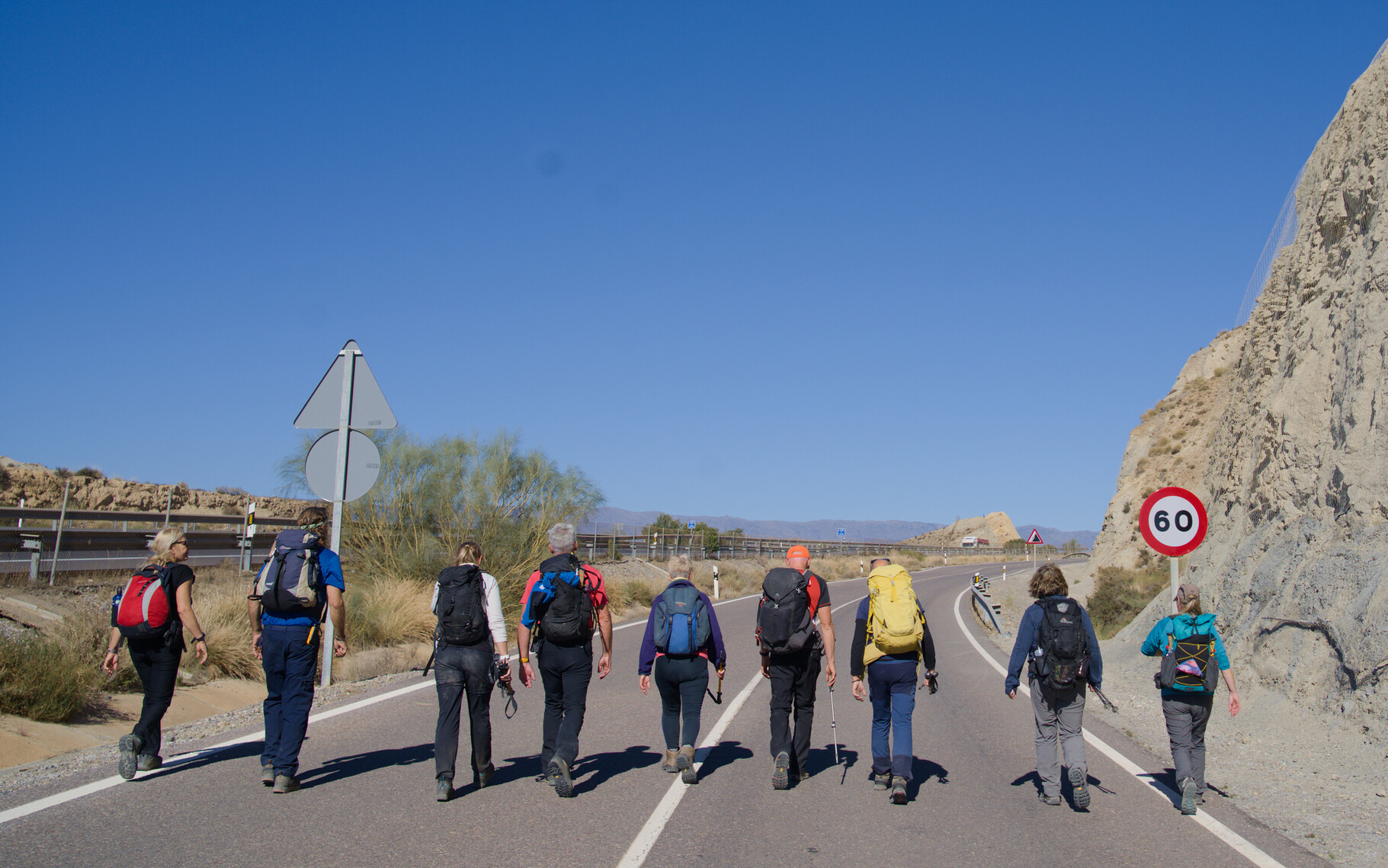 9 persons walking along a deserted country road in Spain