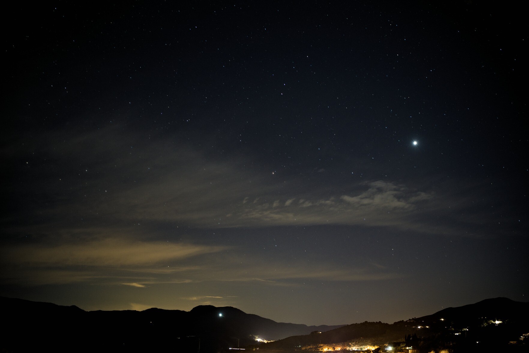 Beautiful star covered sky with lights from a village in the bottom of the screen