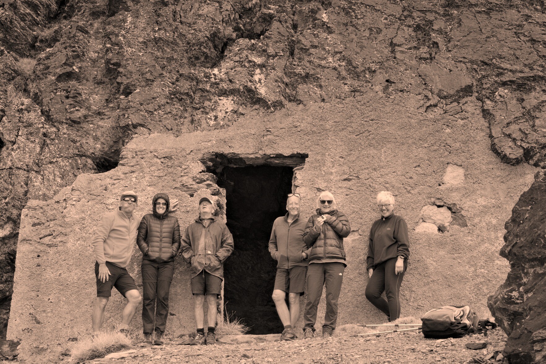 Old "looking" photo with 6 people standing outside a cliff face which has a door cut into it.