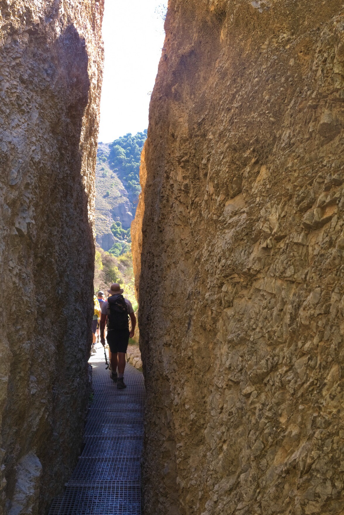 A narrow sliver of space between two large rock walls allows the hiker passage through