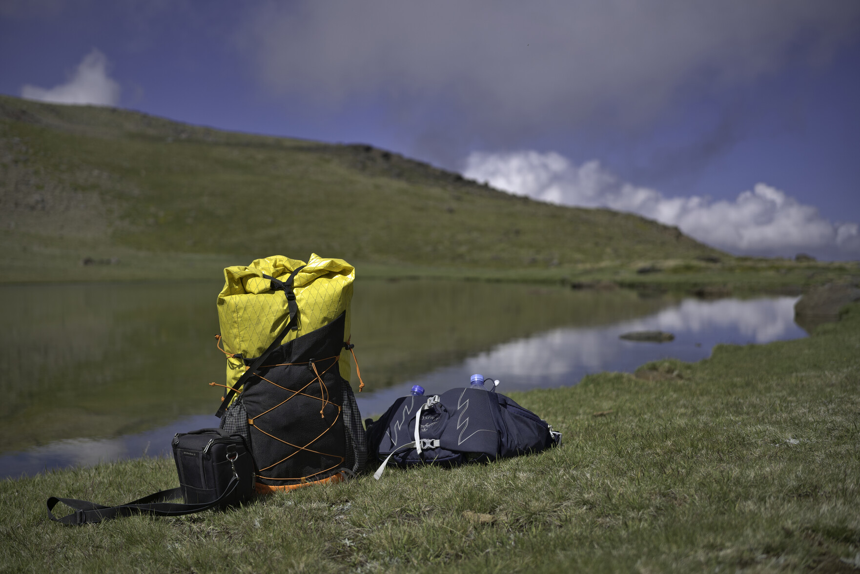 A yellow rucksack sits by the serene waters of the Laguna del Peñon Negro lake