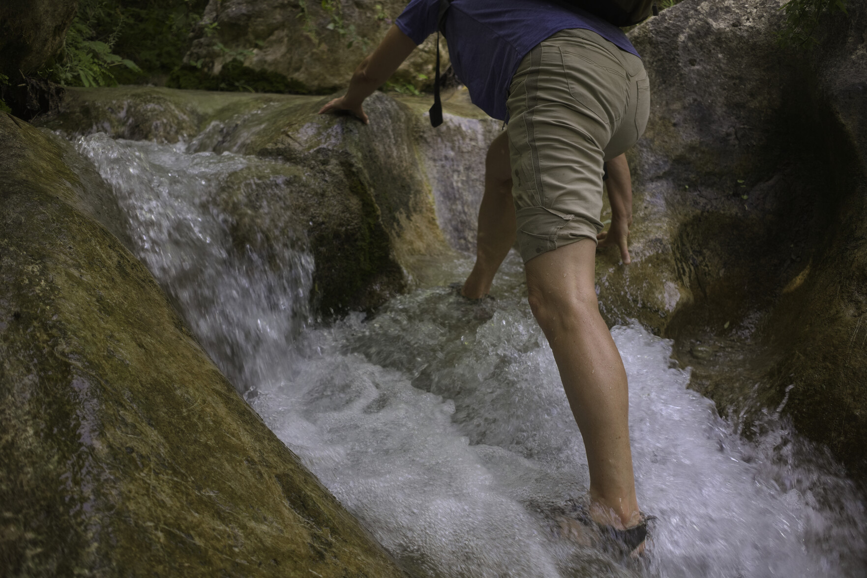 A hiker makes her way up through a small waterfall