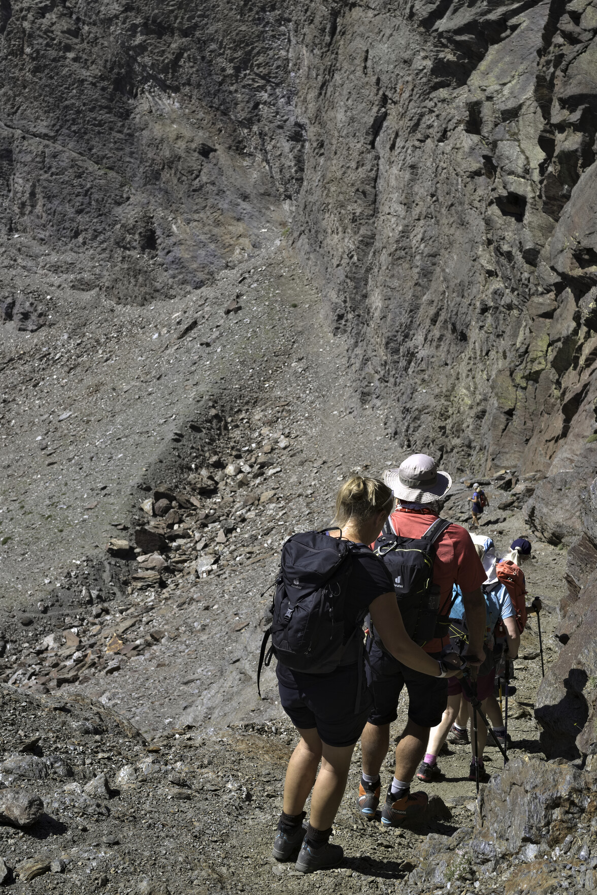 A group of hikers descends a path surrounded by rock walls