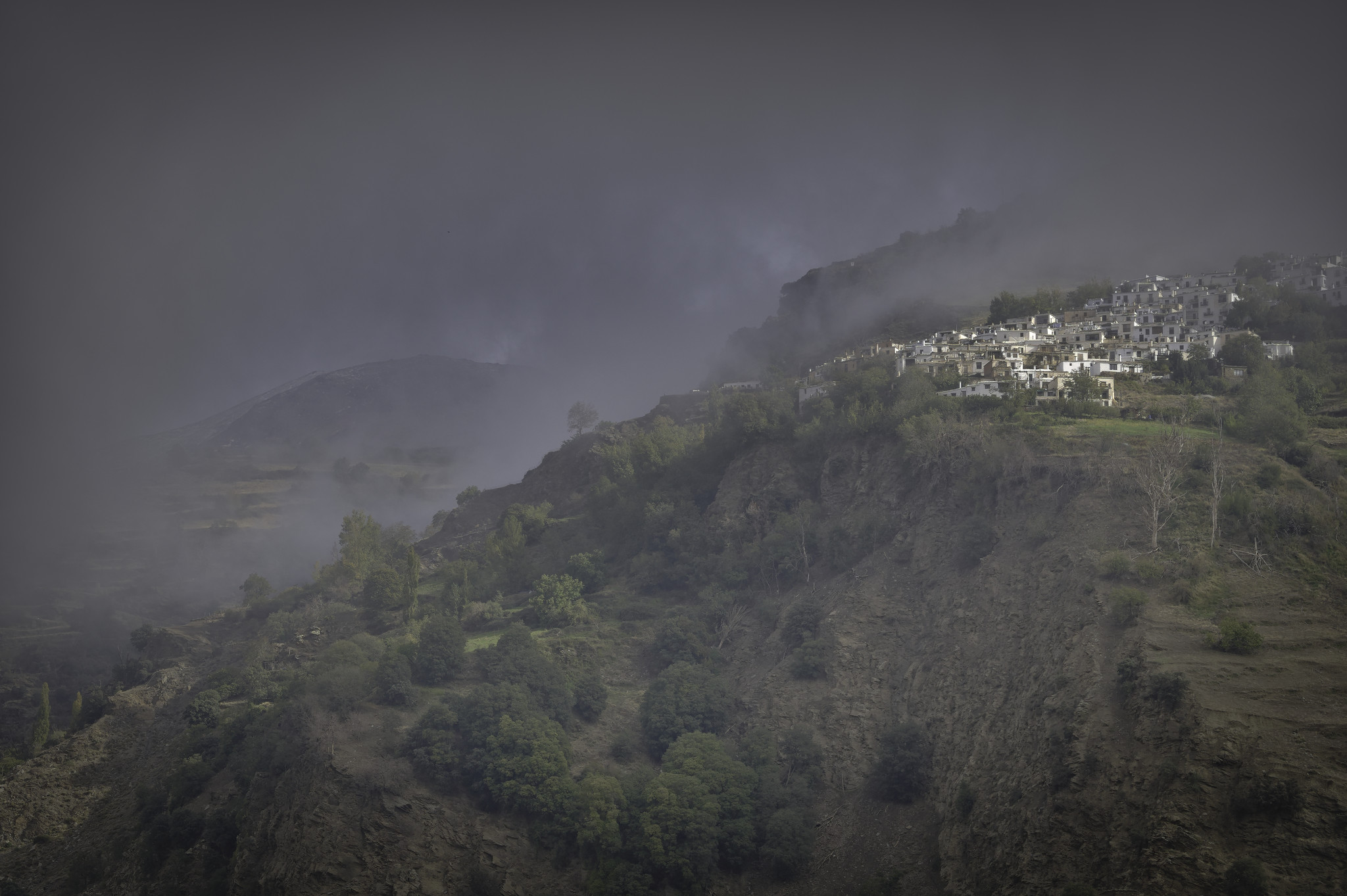 Out of the cloudy grayness in the top right the village of Capileira emerges on a small plateau