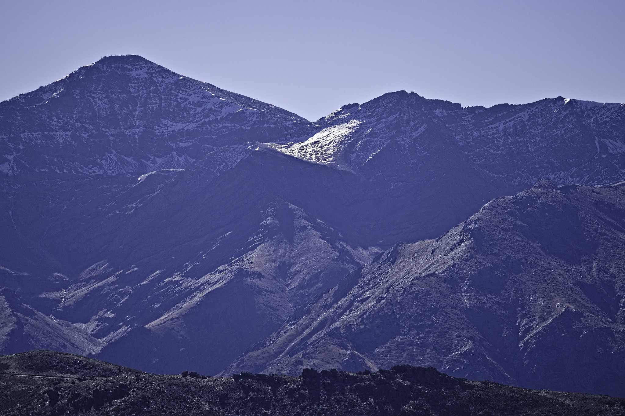 The vertical north face of Mulhacen is on the left with the Puntal de la Caldera to it's right. Much of the faces are in shadow but some sun glints on some of the isolated snowfields