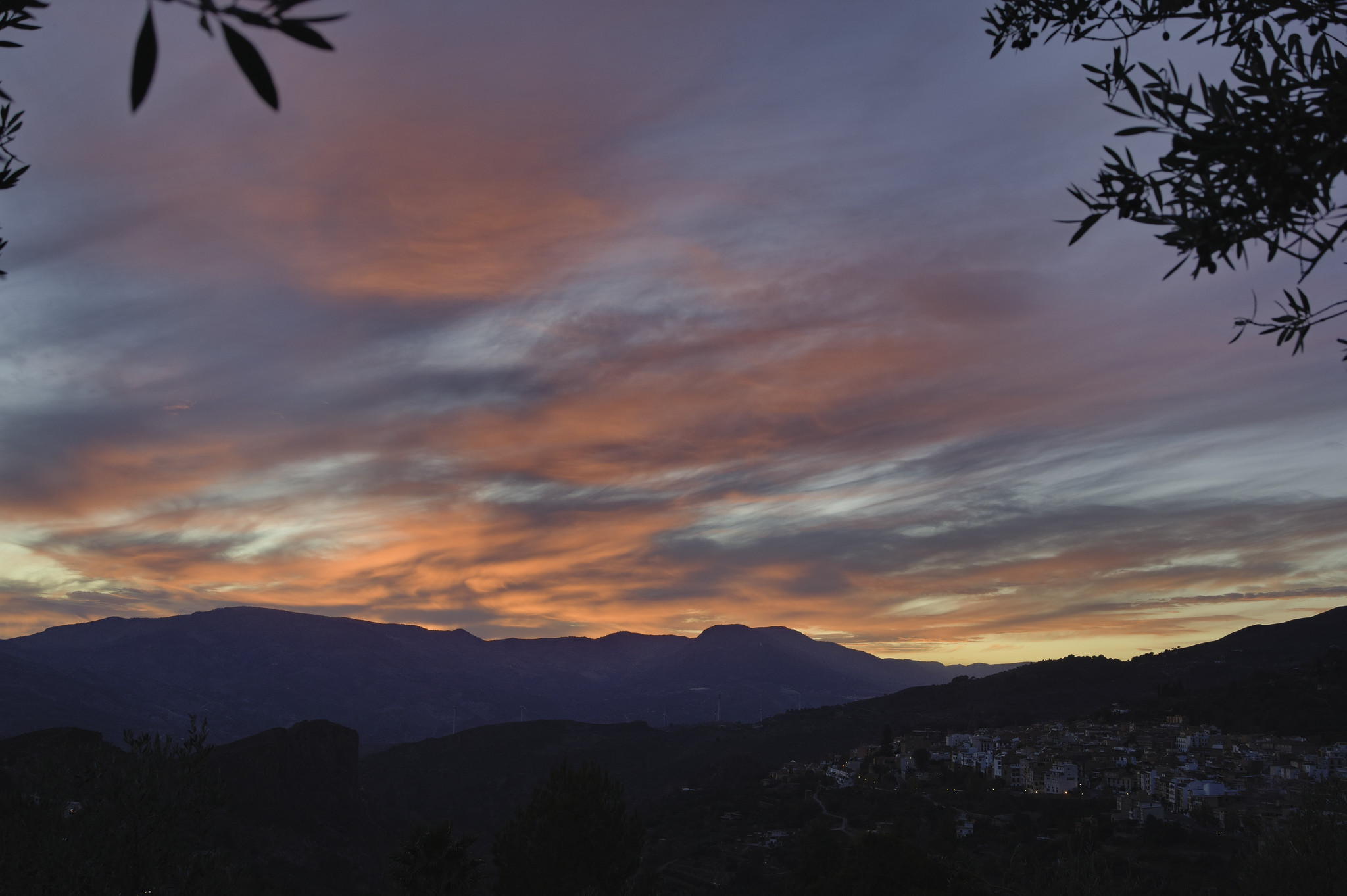 A red and orange sunset sky contrasts with the evening blue and the dark shadows of the hills