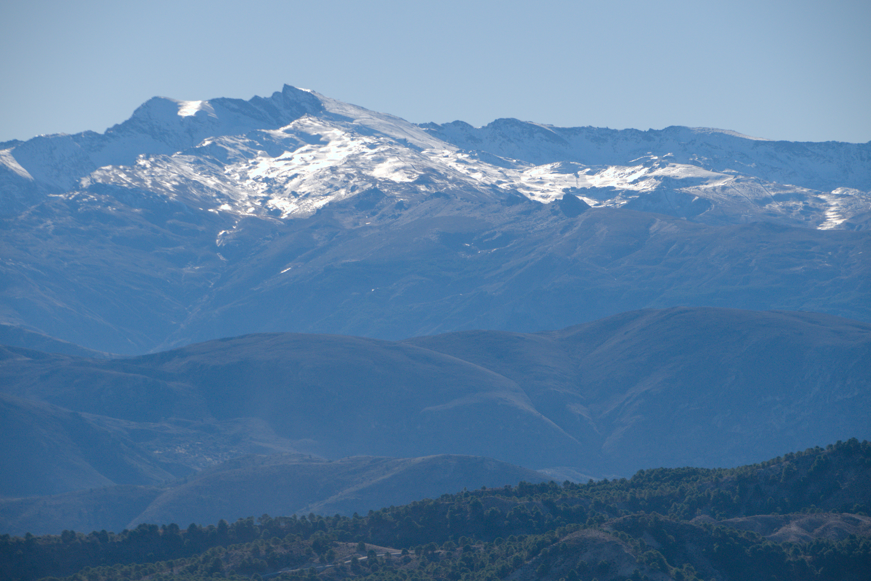 Veleta peak on Spain's Sierra Nevada. Snow and ice from 2700m upwards. The lower slopes a mix of open hillsides and lush pine forests