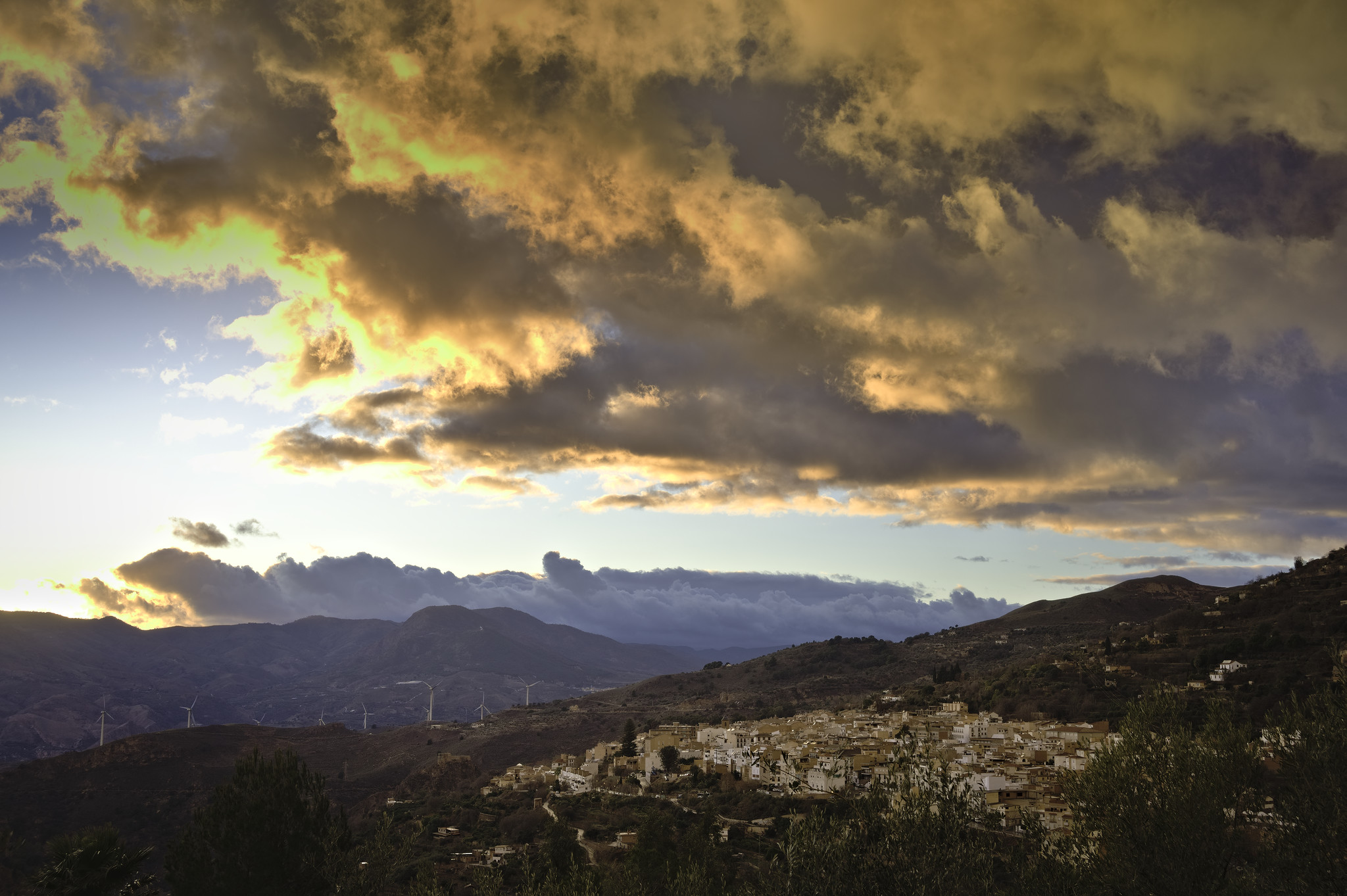 Colorful orange and gray storm clouds dominate the skies over a spanish town