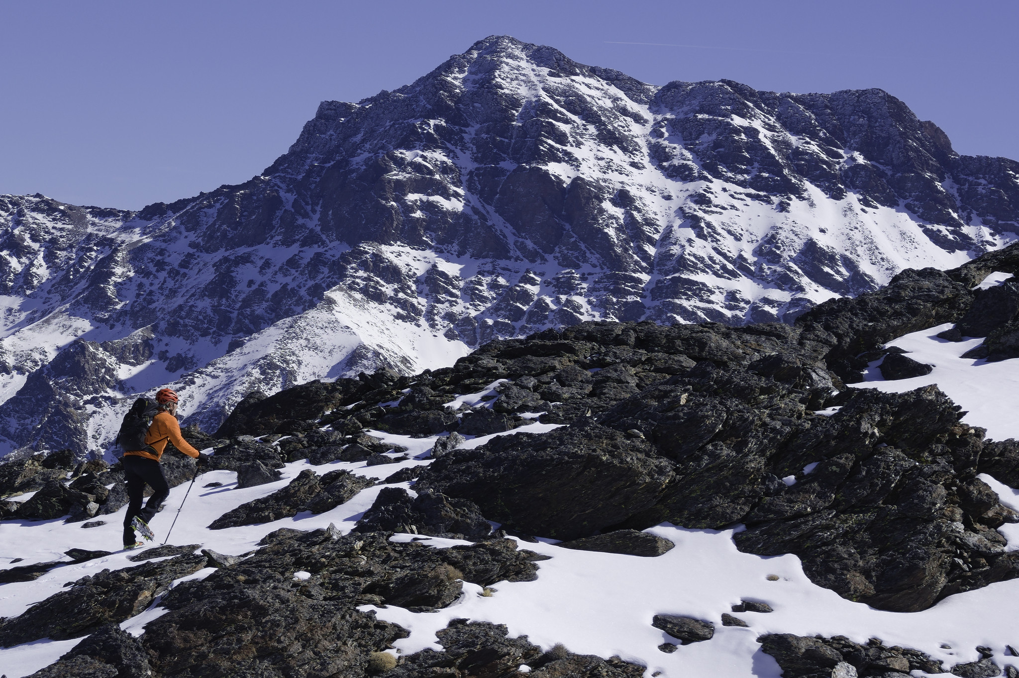 The magnificent north west face of Alcazaba (3350m) with a mountaineer in orange jacket in the foreground.
