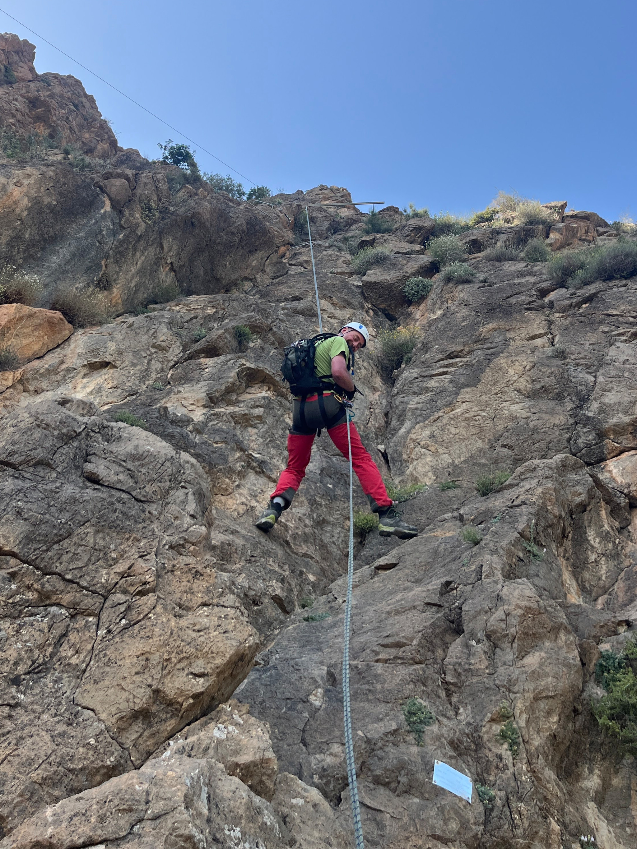 A person abseils down a steep cliff
