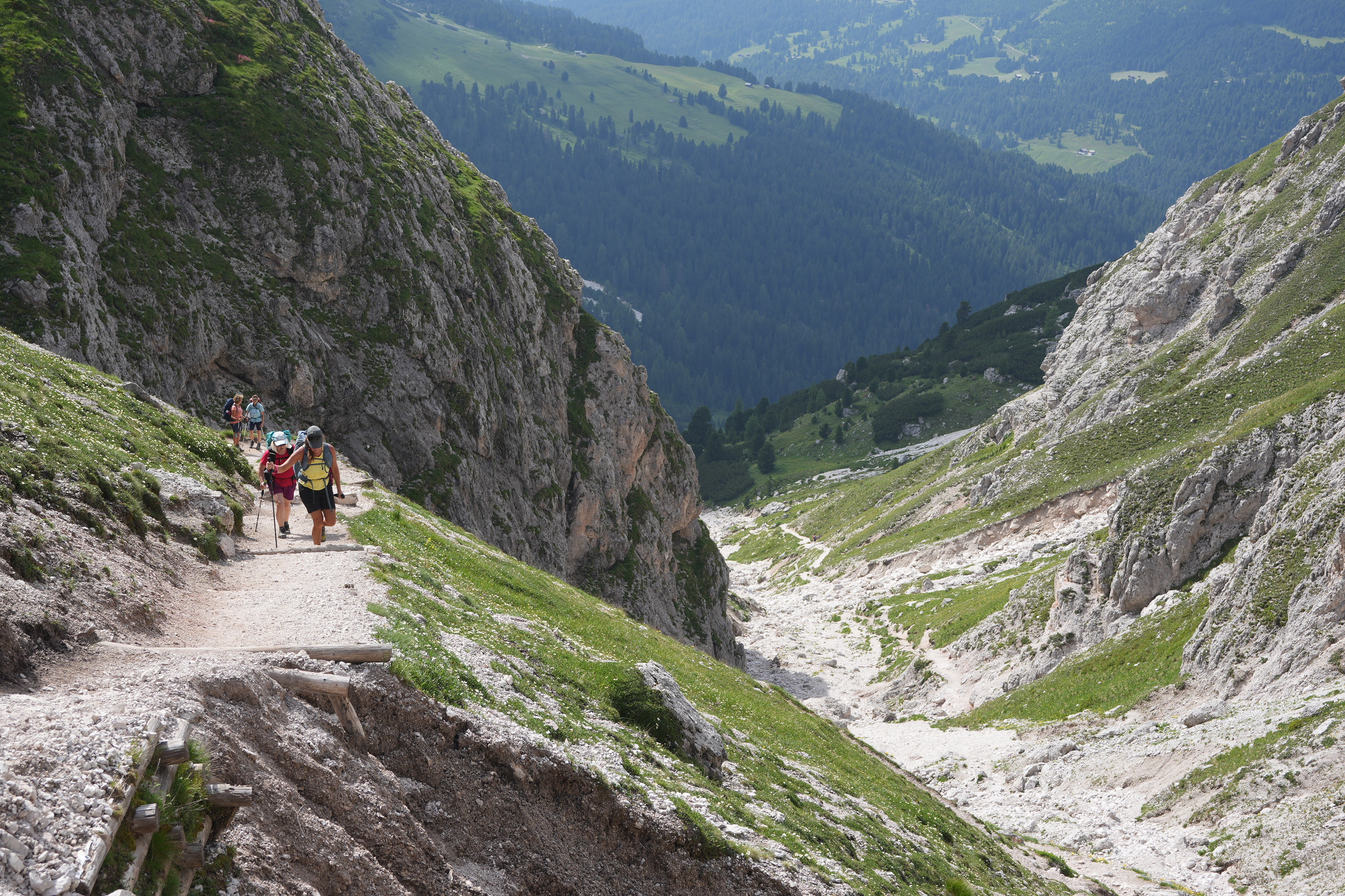 Hikers walk up a track alongside a spectacular rocky valley