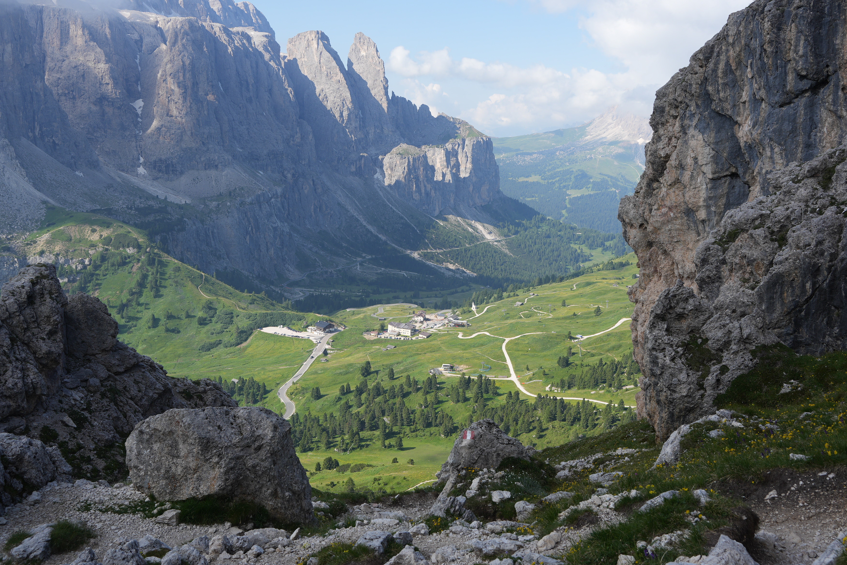 Looking down a rocky pass towards some green alpine meadows