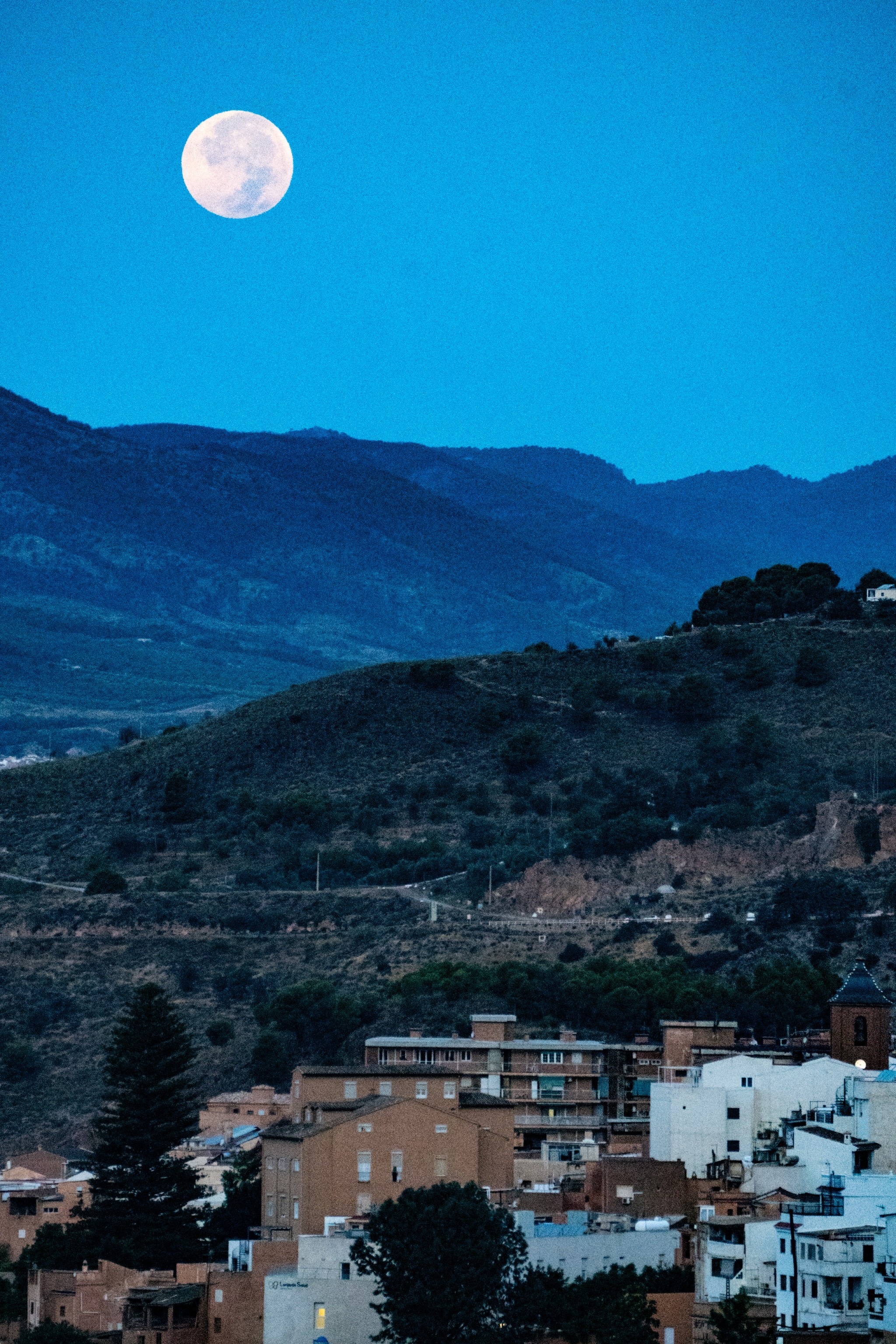 Early morning and the moon sets above a small Spanish town