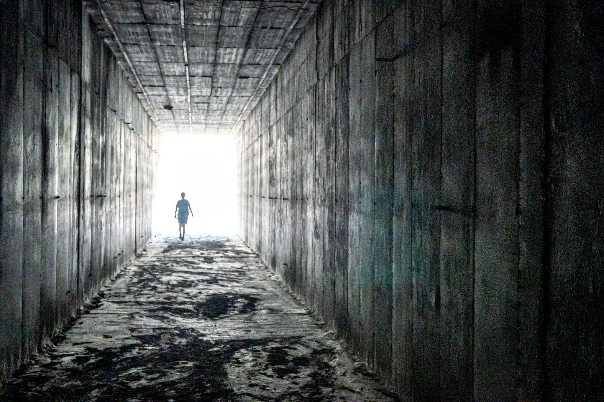 A person stands in the light at the end of a long dark tunnel