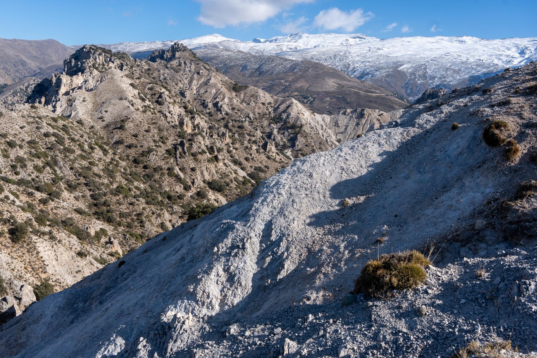 The arid terrain in the foreground contrasts with the high mountain snows behind