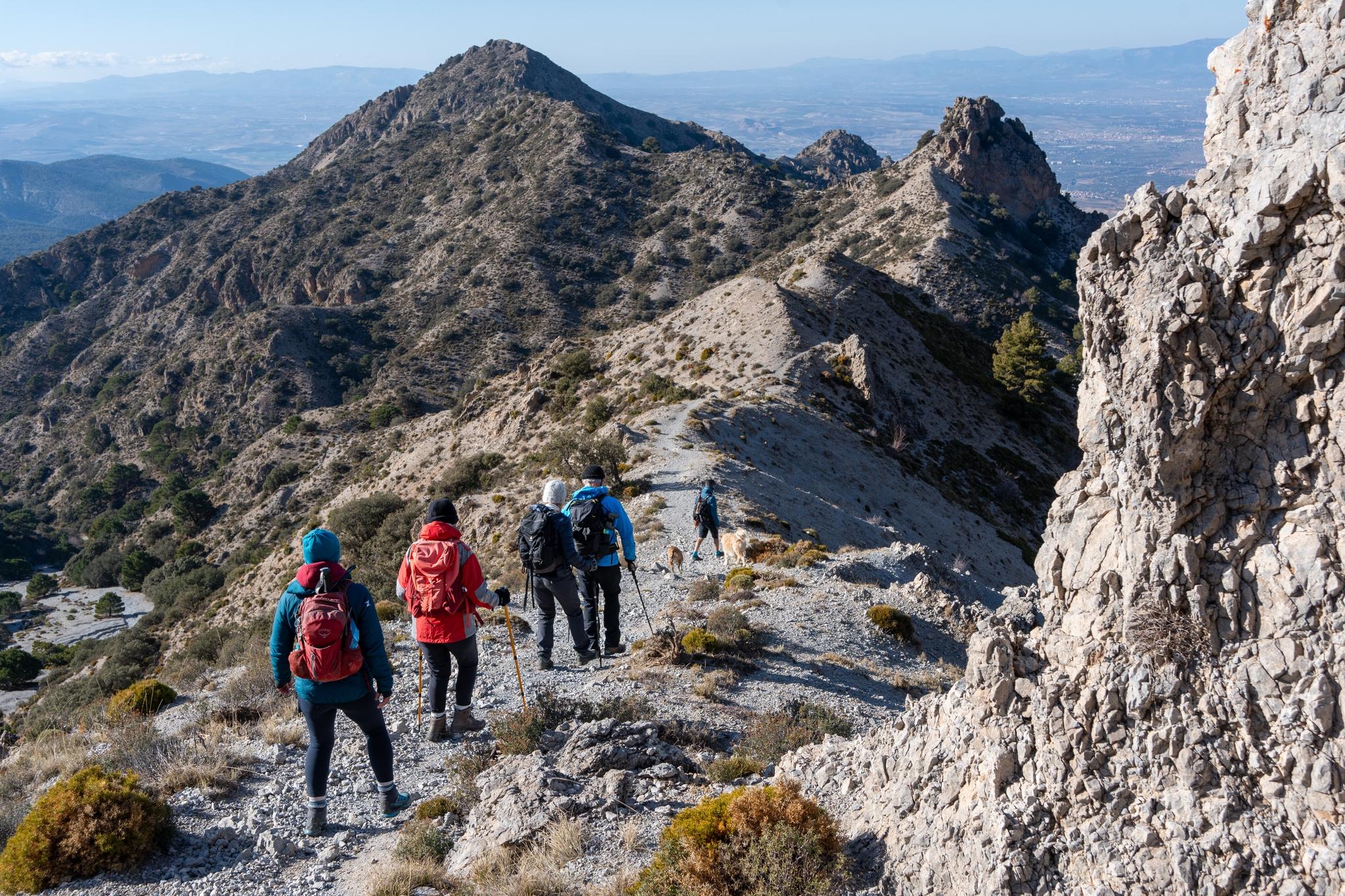 Hikers descending along the ridge towards the peak of Picacho Alto