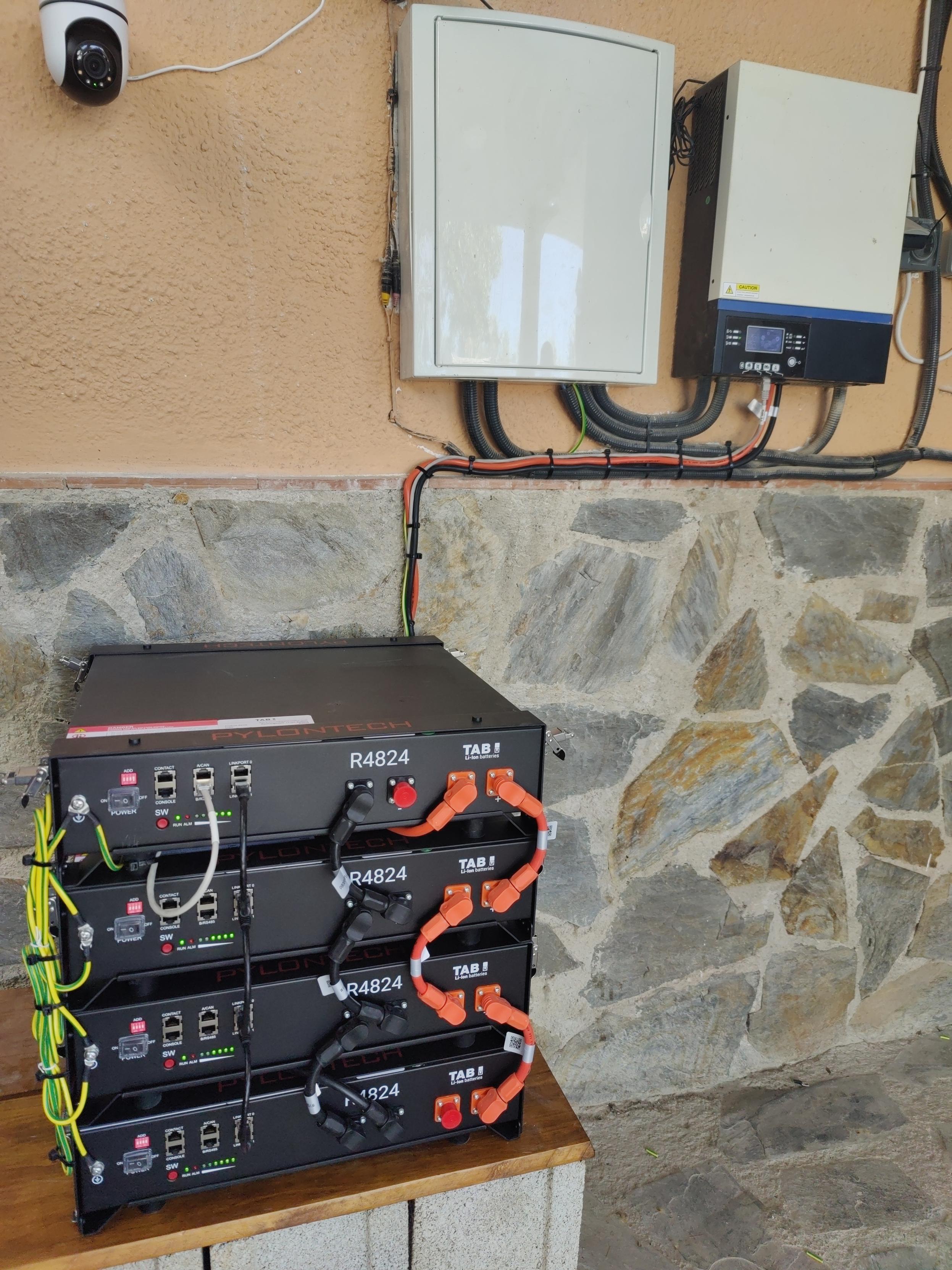 4 lithium batteries are stacked on top of one another. Wires run up the wall behind