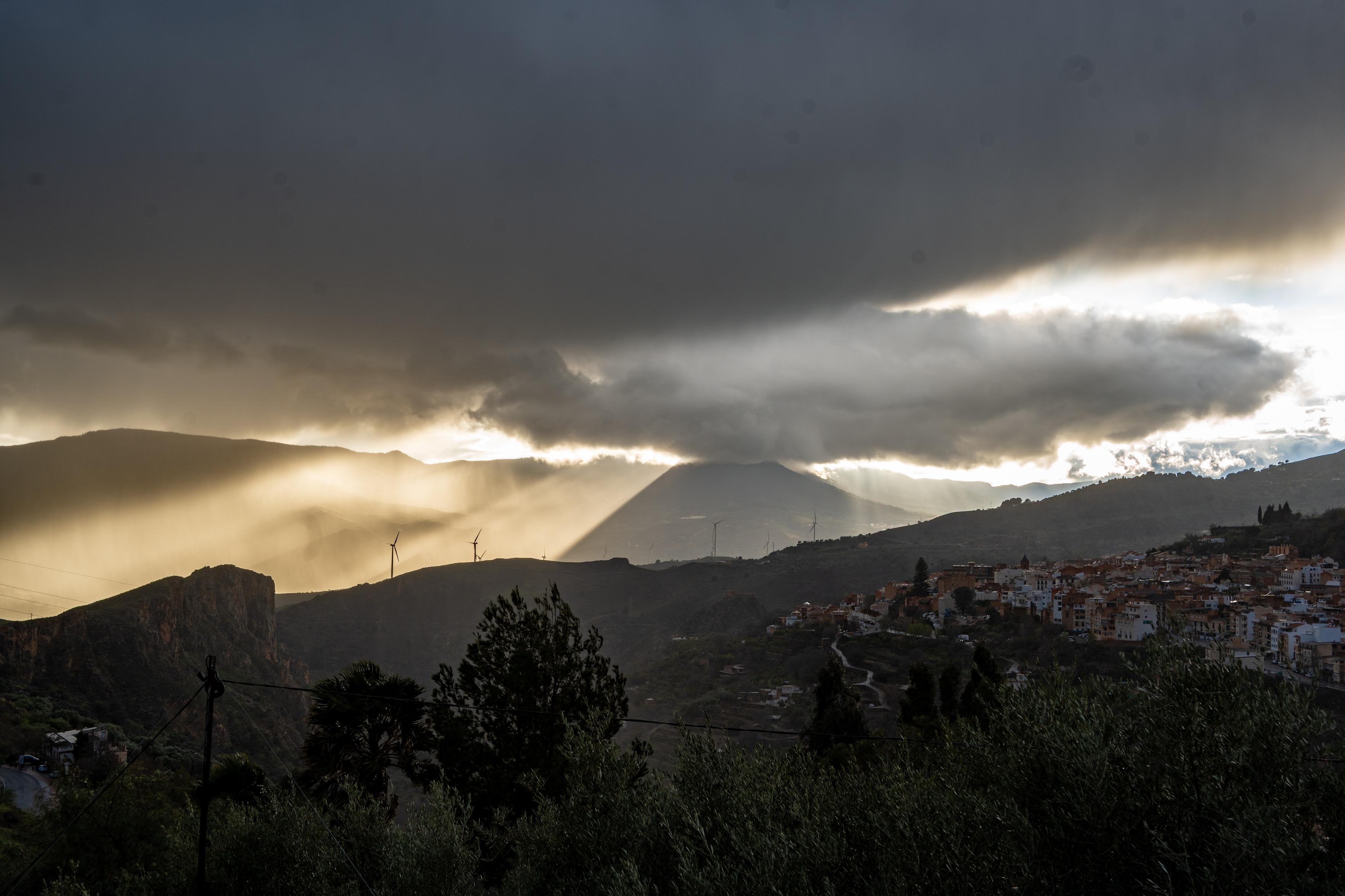 Dusk over Lanjaron in southern Spain and dark threatening clouds merge with evening sunlight