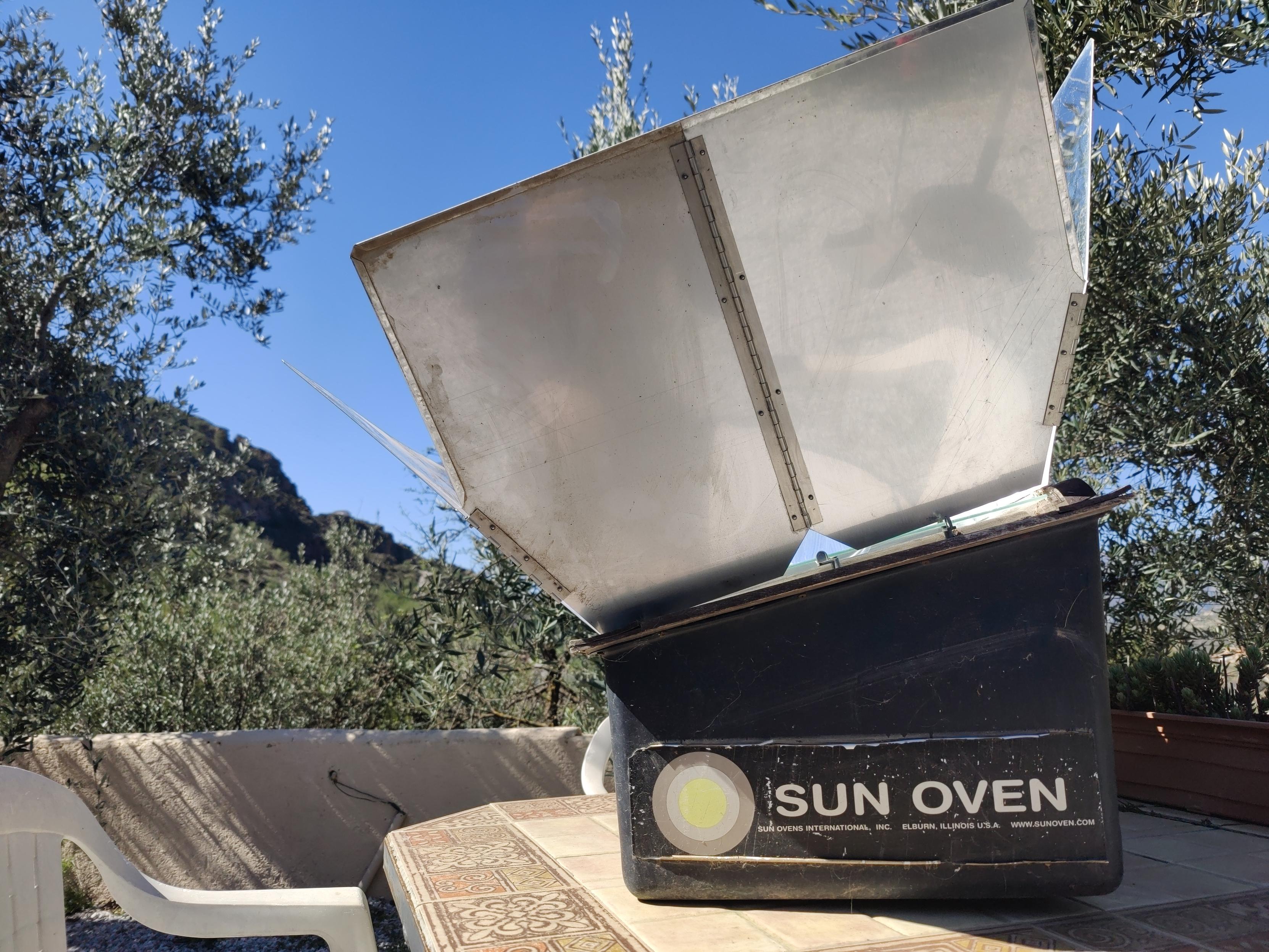 A parabolic shield is open allowing the sun into a sun oven