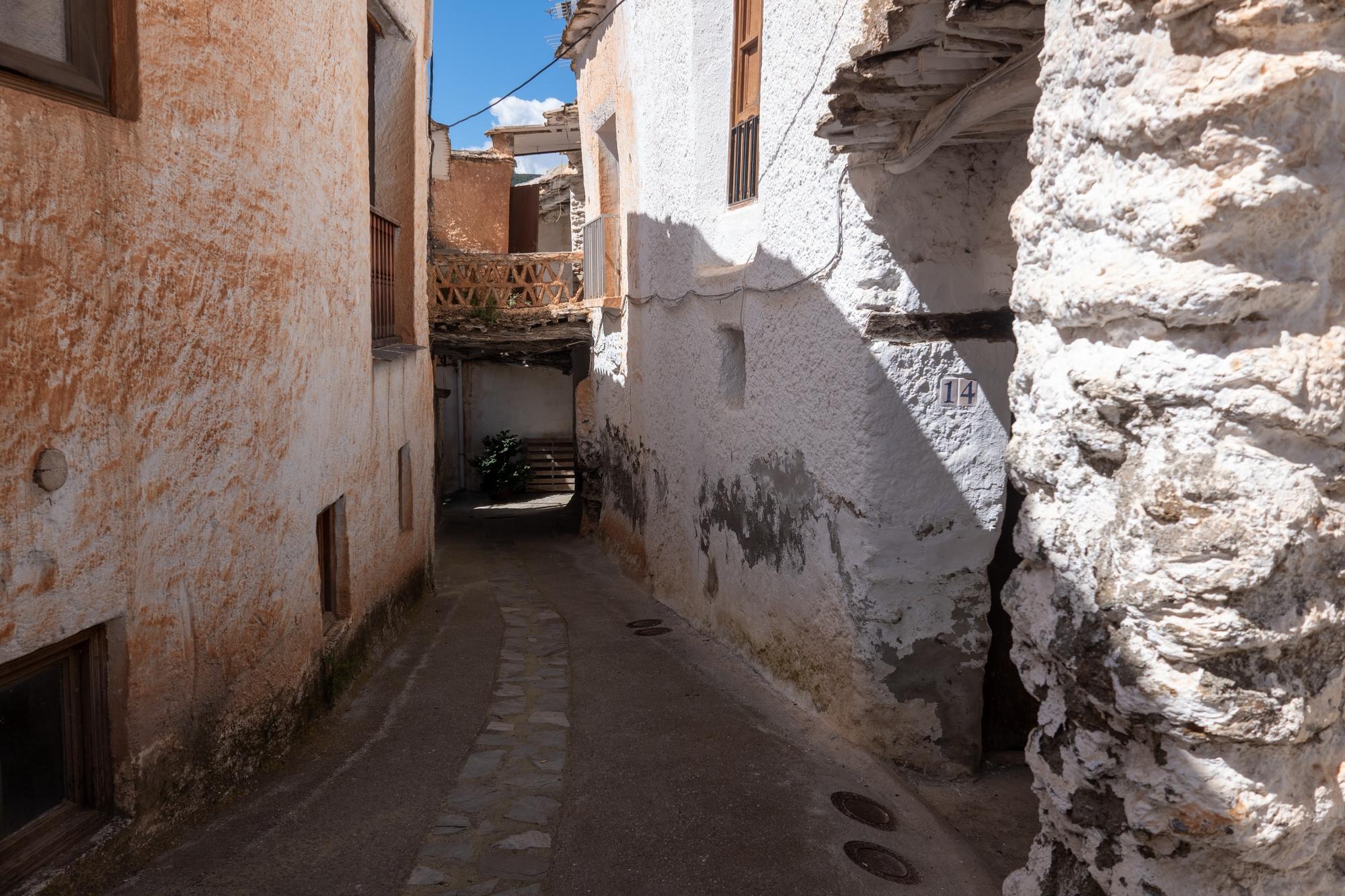 A narrow street with white walled houses, some terracota colour after being affected by the Calima Sahara dust storms