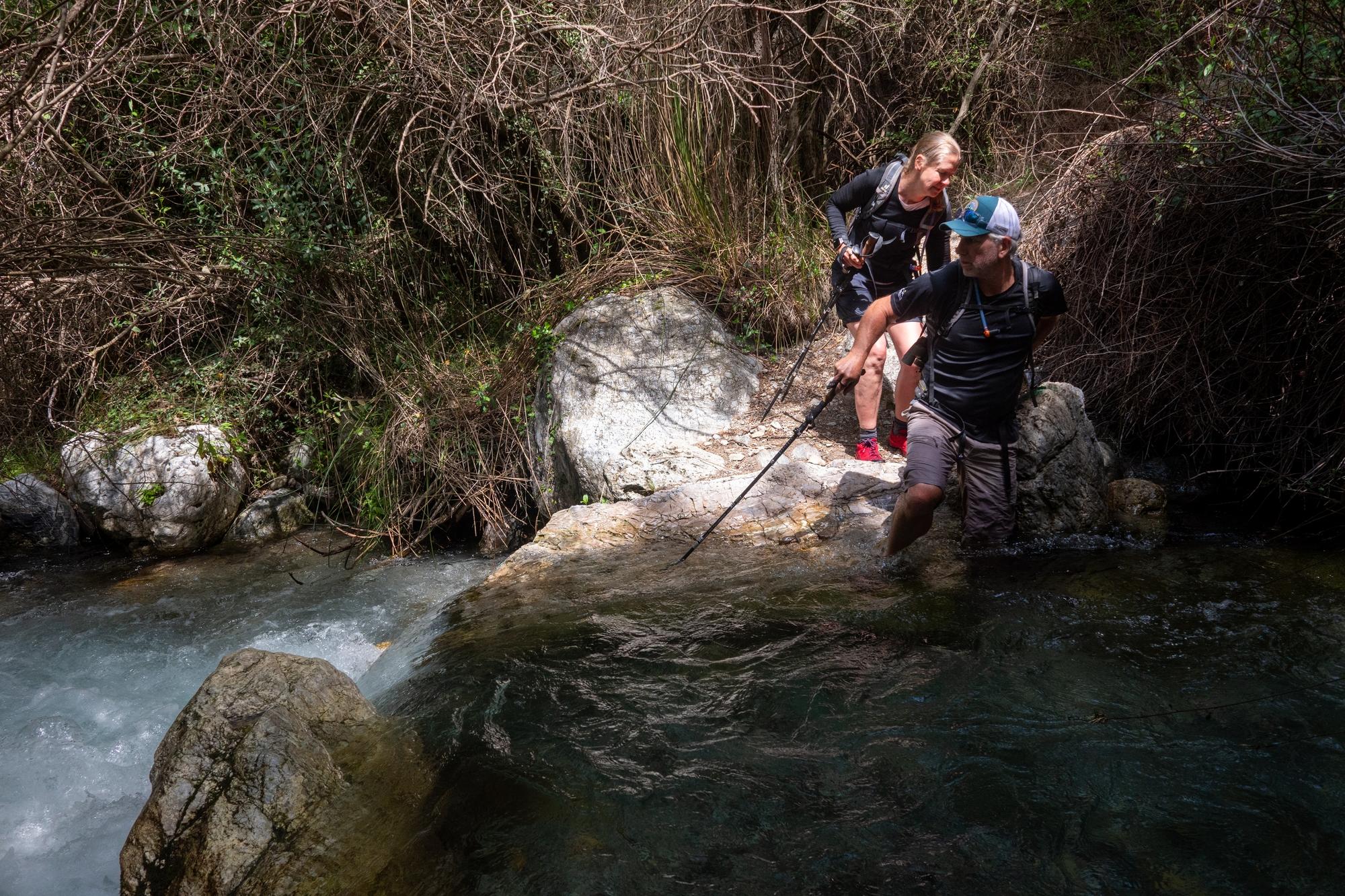 Two hikers entering a fast flowing stream