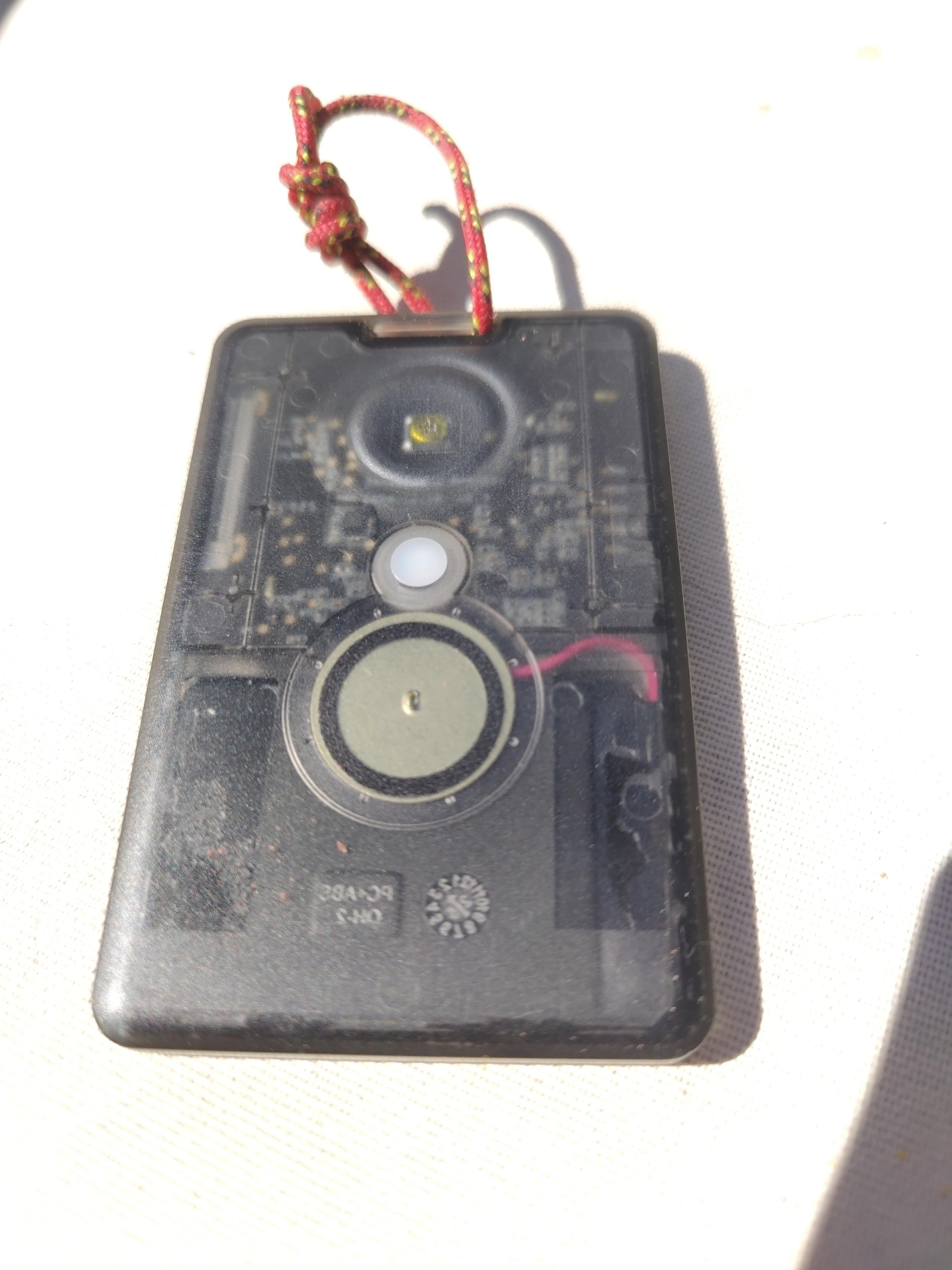 A credit card sized SenseCap tracker T1000-E with a small rope lanyard attached to the top