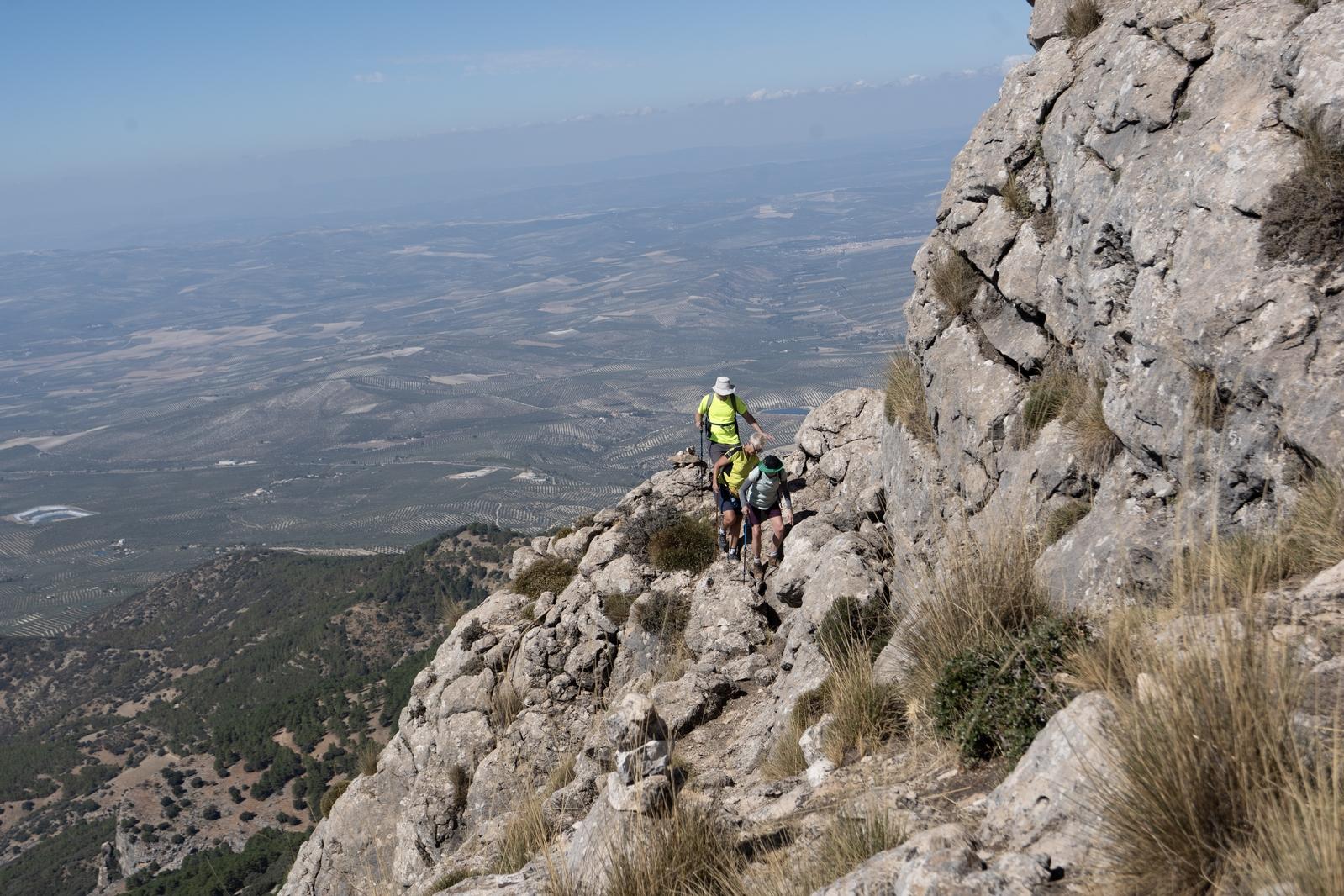 The traverse round the peak to attain the summit. 3 hikers negotiate a narrow path
