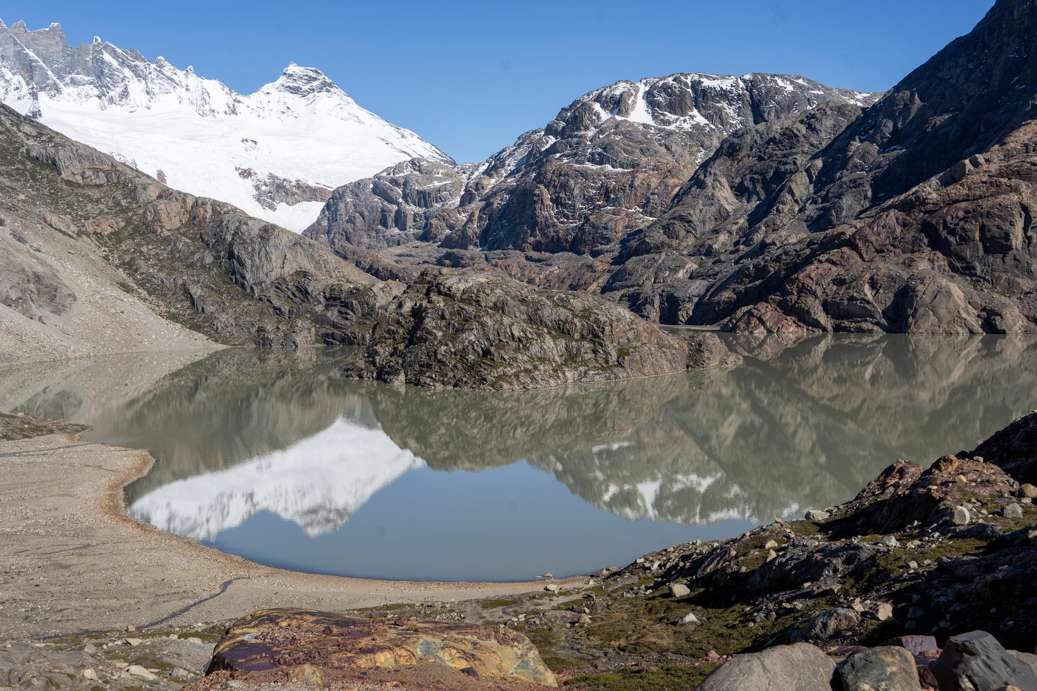 Marconi Norte snow peak reflected in the waters of the Lago Electrico. The Rio Pollone entering the lake from the left